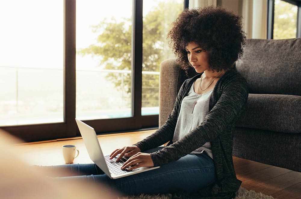 Anywhere Operations: Woman sitting on floor of her home working on laptop